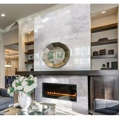 a living room filled with furniture and a fire place next to a wall mounted fireplace