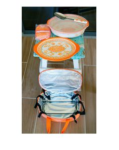 three pieces of luggage sitting on top of a tiled floor next to each other with orange handles