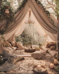 a canopy bed in the middle of a forest with candles on it and greenery hanging from the ceiling