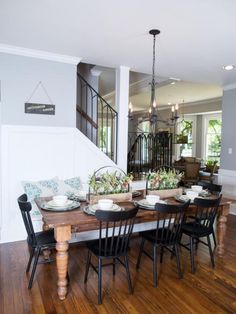 the dining room table is set for six with black chairs and white plates on it