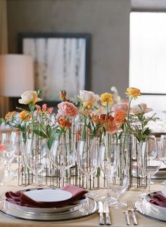 there are many vases with flowers in them on the table set for an event