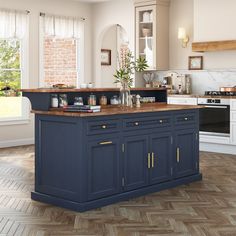 a large kitchen with an island in the middle and wooden flooring on the other side