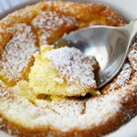 a powdered sugar covered pastry in a white bowl with a spoon sticking out of it