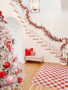 a decorated christmas tree sitting in the middle of a living room next to a staircase