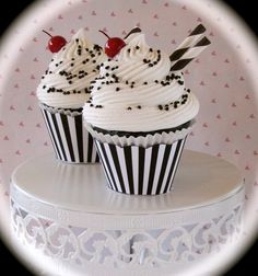 two cupcakes with white frosting and black sprinkles on top