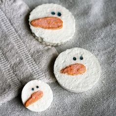 three decorated cookies sitting on top of a gray blanket next to two smaller ones with faces