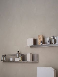 two shelves with various items on them in a room that is painted light gray and white