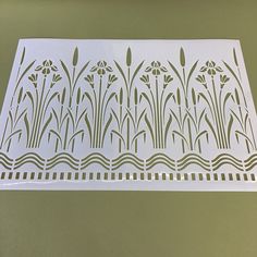 a paper cut out of grass and flowers on a green tablecloth with white border