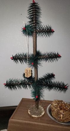 a small christmas tree sitting on top of a wooden table next to a plate of food