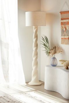 a table with a lamp, vase and stuffed animal on it in front of a window