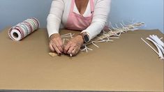 an older woman sitting at a table working on some crafting supplies with scissors and tape