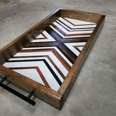 a wooden tray sitting on top of a cement floor covered in black and white tiles