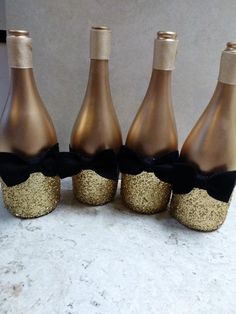 a group of wine bottles with gold glitter and black bows on them are lined up in a row