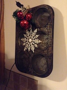 a metal tray with christmas decorations on it hanging from the wall next to a fireplace