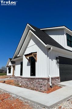 a white house with a black roof and two garages