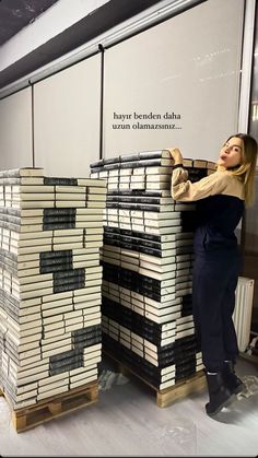 a woman standing next to stacks of books