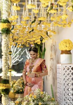 a woman in a pink sari standing under a yellow and white chandelier