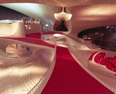 the interior of a modern building with red carpet and stairs leading up to two levels