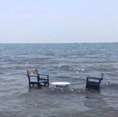 two chairs sitting in the middle of some water