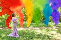 a pregnant woman standing in front of a rainbow colored tree with her hands on her hips