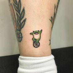 a person with a small tattoo on their leg that has an alligator riding a bike