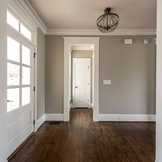 an empty room with hard wood floors and white trim on the doors, windows, and door knobs