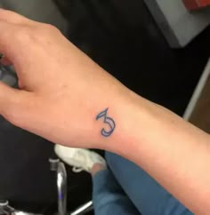 a person with a small tattoo on their left arm and the number five in blue ink