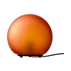 an orange ball shaped lamp on a white surface with a black cord attached to it