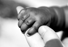 a close up of a person holding the hand of a child's hand on a beach