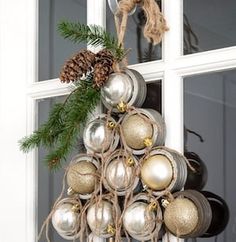 a christmas tree made out of silver and gold baubles hanging from a window