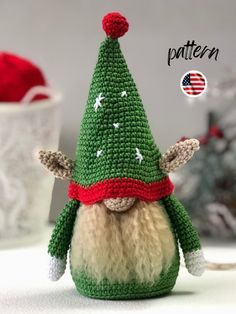 a small crocheted gnome with a red hat and green jacket on it's head