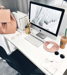 a white desk topped with a computer monitor next to a pink bag