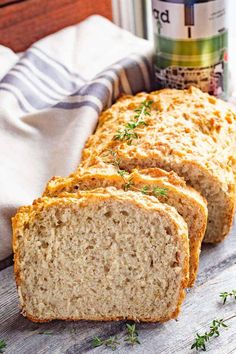 sliced loaf of bread sitting on top of a wooden table next to a jar of beer