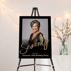 a black and gold birthday party sign sitting on top of a easel next to a vase filled with flowers