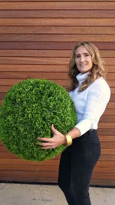 a woman is holding a fake green ball