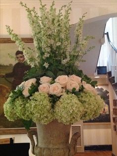 a vase filled with lots of flowers on top of a wooden table next to stairs