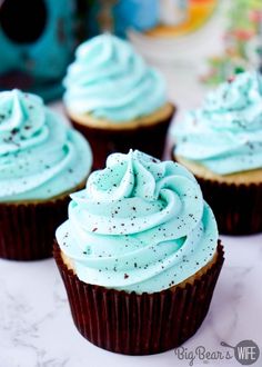 three cupcakes with blue frosting and sprinkles on the top