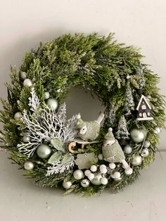 a wreath with white and green decorations on it, including an animal figurine