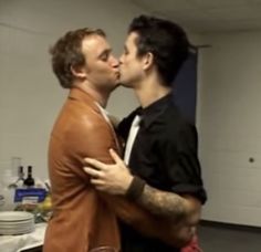 two men are kissing each other in the kitchen