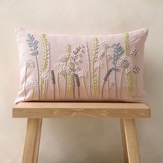 a pink pillow sitting on top of a wooden bench