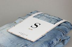 a pair of blue jeans with the letter s on it and a tag attached to them