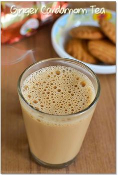 a glass filled with liquid sitting on top of a table next to a plate of cookies