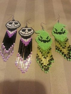 three pairs of beaded earrings with faces on them sitting on top of a table