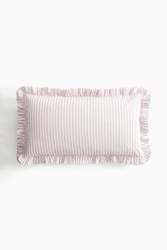 a white and pink striped pillow sitting on top of a bed