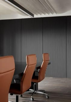 an empty conference room with leather chairs and a black table in front of a striped wall