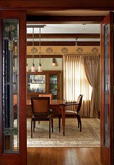 an open door leading to a dining room with wooden floors and walls in the background