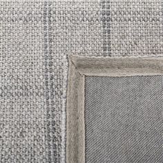 the corner of a gray and white rug with an empty square in it's center