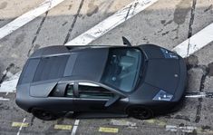 an overhead view of a black sports car parked on the street with no one around