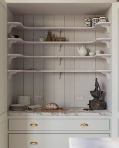 a kitchen with white cupboards and shelves filled with dishes on top of each other