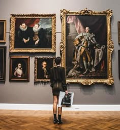 a woman standing in front of some paintings